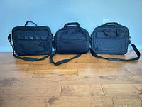 All three black laptop bags lined up side by side on floor
