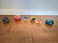 All six glass paperweights lined up on floor