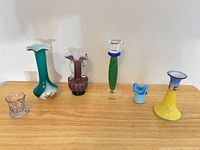 Front view of six of the seven mini vases lined up on wooden surface