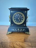 Front view showing full clock, dial, bezel, feet and decorative gold scrollwork