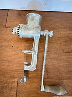 Left side view of complete meat grinder showing body, handle, clamp mechanism