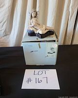 Front view of Lladró Fantasia Azul reclining fairy figurine resting on its original box