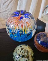 Large reef scene glass paperweight with dolphins and fish beside smaller abstract piece