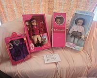 Group shot of three boxed dolls and two boxed outfits on sofa