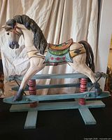 Full view of rocking horse on teal slat base