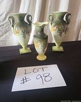 Front view of all three porcelain vases displaying hand-painted grape motif, ombré coloring, square bases on two