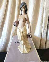 Left-front view of Lladró Water Girl figurine standing on box, showing jugs and skirt details