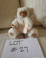 Full frontal view of bear seated holding bow and arrow, showing sash and tags