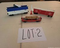 Three Lionel O gauge train cars laid out: Minuteman gondola, Target boxcar, flatcar with logs