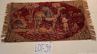 Full view of woven tapestry rug with camel desert scene and fringe
