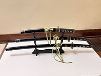 Three swords sheathed on black wooden stand