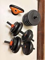 Full set laid out: two assembled dumbbells, plates stack, kettlebell handle visible