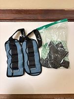 Pair of blue adjustable weight straps adjacent to sealed bag of inserts