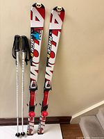 Full view of both Atomic Race 8 skis with mounted bindings and pair of ski poles