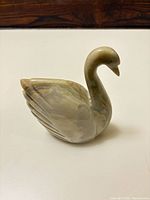 Front three-quarter view of stone swan showing carved wings and neck