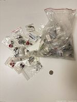 Pile of individual bagged jewellery pieces with coin for scale