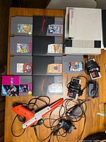 Overall shot showing console, nine game cartridges, two controllers, Zapper, power adapter, RF switch