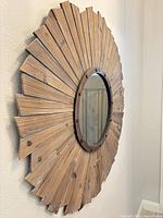 Side view of mirror showing wood sunburst frame and metal inner ring