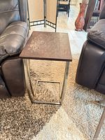 Front angled view of table between sofas showing wood top wear and metal C-frame