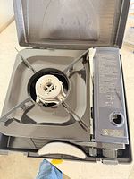 Open case showing full CI-153S stove, burner, pot supports and control panel