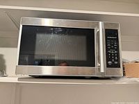 Front view of Hamilton Beach stainless steel microwave on shelf