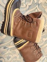 Side view of both boots showing uppers, laces, and rubber lowers