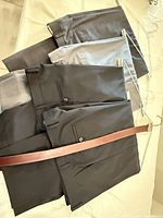 Four pairs of trousers folded on hanger, colors visible