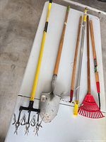 All long-handled garden tools laid on table