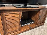 Front view showing TV stand, louvered doors, open center with electronics
