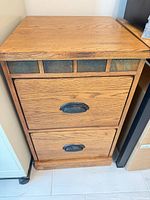 Front view of two-drawer oak veneer cabinet with decorative panel insets and metal cup pulls