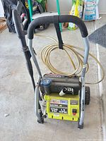 Front view of Ryobi pressure washer showing label, wheels, wand, hose and soap tank