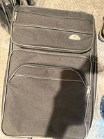 Front view of black Samsonite softside suitcase showing two exterior zip compartments and logo badge