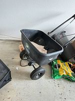 Front oblique view of spreader showing hopper, wheels and handle