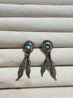 Front view of both earrings showing bear paw design, turquoise stones, and feather drops