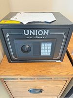Front view of Union Safe Company black electronic safe on wooden stand