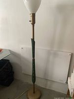 Full view of tall wooden and metal floor lamp with milk glass shade
