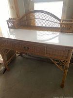 Full view of wicker desk showing drawer, legs, hutch and white top