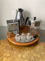 Group view of all items: Thermos carafe, glass coffee pot, chrome napkin holder, salt and pepper shakers in caddy