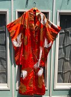 Full front view of orange silk uchikake with crane embroidery