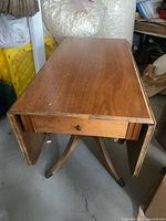 Full view of drop-leaf table folded down showing drawer and pedestal legs