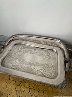 Two large silver-plated trays stacked, showing overall size and shape