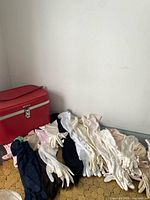 Red makeup case with pile of assorted gloves