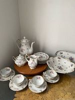 Full view of porcelain set including teapot, sugar, creamer, plates, bowls, cups and saucers
