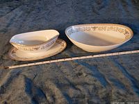 Both gravy boats and underplate with measuring tape for scale
