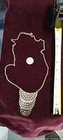 Gold-tone geometric bib necklace with measuring tape and coin for scale