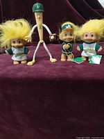 Group view of three troll dolls and bat figure on cloth backdrop