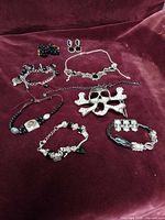 Group shot of all nine jewelry pieces laid out on burgundy surface