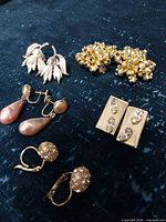 All five earring pairs arranged on dark fabric
