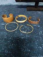 Five bracelets laid out showing variety of styles and metals