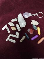 Overview of all quartz points, polished stones and amethyst keychain on burgundy background